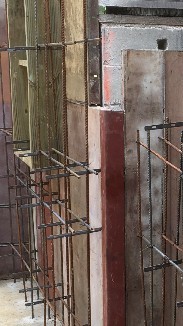 Close-up of steel reinforcement bars and wooden and metal formwork panels used in concrete construction.